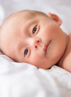 Baby boy (0-1 months) lying on bed