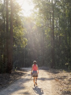 Australia, New South Wales, Port Macquarie, Rear view of mature woman walking along dirt road in forest