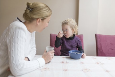 Mother looking at daughter (4-5) eating breakfast