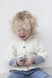 Portrait of blond girl (4-5) playing with mobile phone