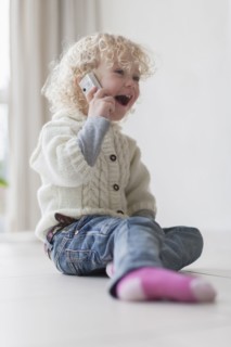 Blond girl (4-5) playing with mobile phone