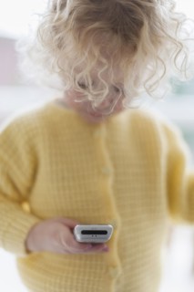 Blond girl (4-5) playing with mobile phone