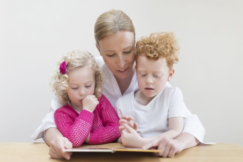 Mother reading book to son (8-9) and daughter (4-5)