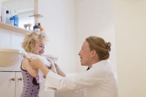 Mother helping daughter (4-5) get dressed