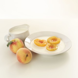 Halved peaches in bowl of cream.