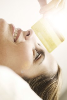 Portrait of smiling mid adult woman lying down and looking at credit card.