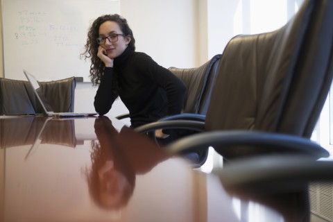 Portrait of young business woman sitting in conference room with laptop.