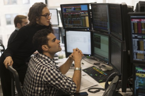 Young traders analyzing computer data.