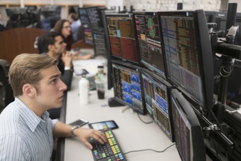Young traders analyzing computer data.