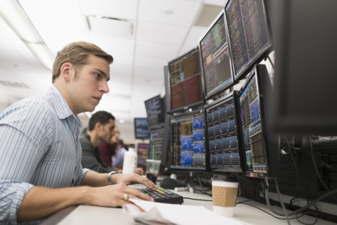 Young traders analyzing computer data.