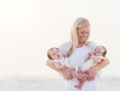 Happy mid adult mother carrying two baby girls (2-5 months)