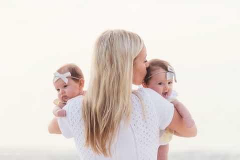 Happy mid adult mother kissing one of baby girls (2-5 months)