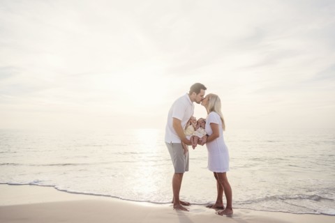 Couple with twins (2-5 months) kissing on seashore