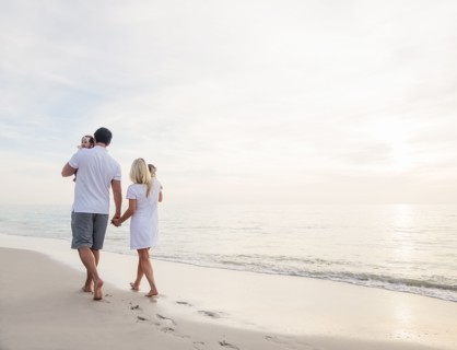 Couple with twins (2-5 months) walking along seashore
