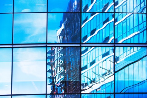 USA, New York, Clouds and residential building reflecting in glassy office building