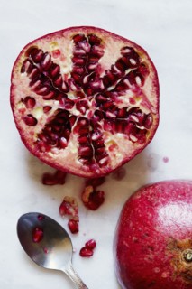 Halved Pomegranate and spoon against white background