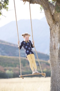 Girl (4-5) standing on swing