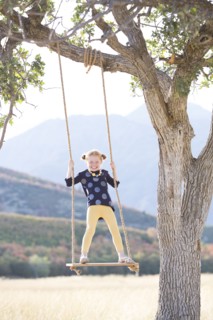 Girl (4-5) standing on swing