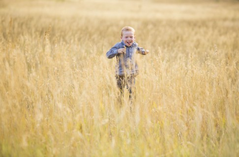 Boy (4-5) running in dry grass