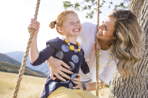 Mother with girl (4-5) sitting on swing