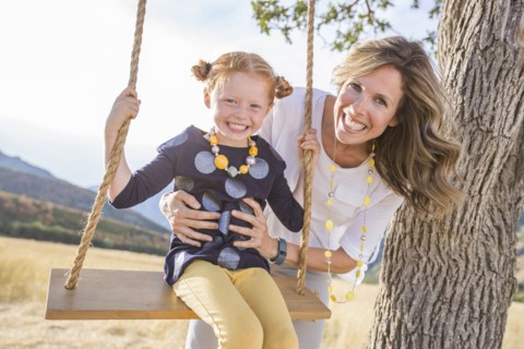 Mother with girl (4-5) sitting on swing