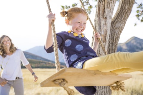 Mother with girl (4-5) sitting on swing