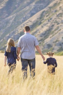 Father with two daughters (4-5, 8-9) walking in field