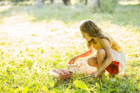 Girl with fruit crouching in grass