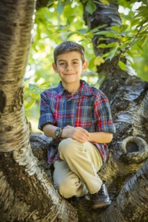 Smiling boy sitting on tree