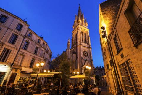 France, Occitanie, Montpellier, Sidewalk cafe and St. Anne Church at dusk