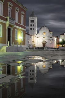 Croatia, Zadar, Buildings reflecting in puddle at dusk
