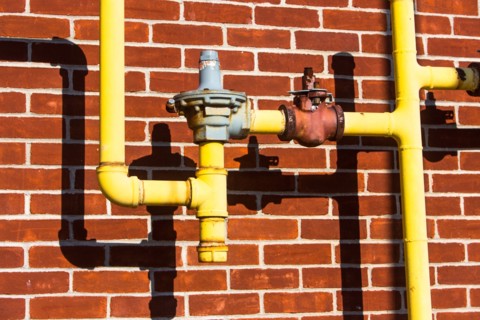 Close up of pipes in front of brick wall