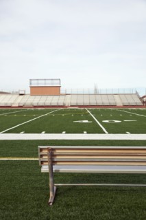 American football field with bench in foreground and empty bleachers in background