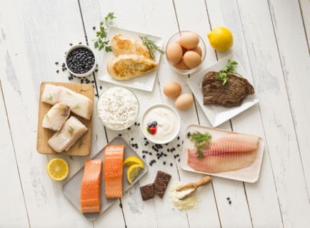 Chicken meat, fish, cottage cheese, yogurt and eggs on white table