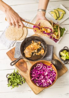 Woman preparing tortilla with tilapia and red cabbage