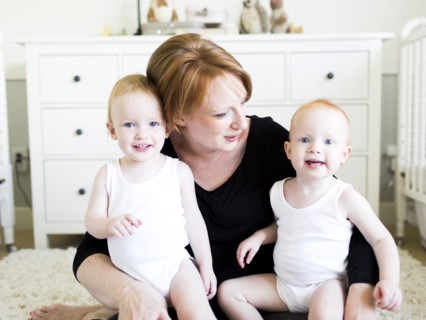 Portrait of mother holding sons (12-17 months) in nursery