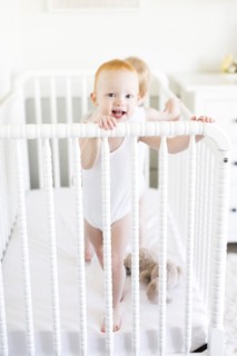 Twin brothers (12-17 months) standing in crib