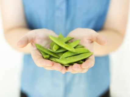Woman wearing blue top holding sugar snap peas