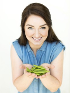 Woman wearing blue top holding sugar snap peas