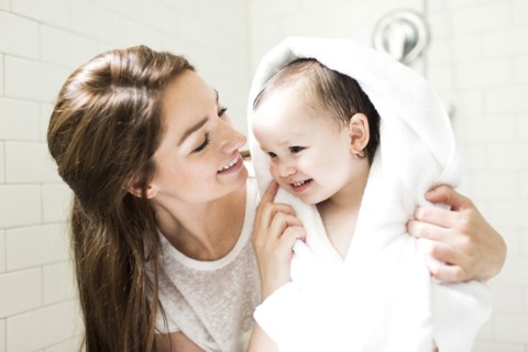Mother wrapping son (4-5)  in towel in bathroom