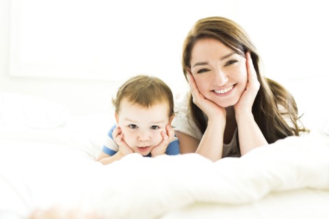 Mother and son (4-5) lying on bed  and smiling