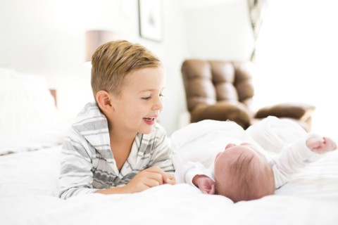 Brother (4-5) and sister (0-1 months) lying on bed