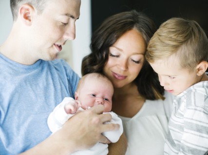 Mother and father carrying son (4-5) and daughter (0-1 months)