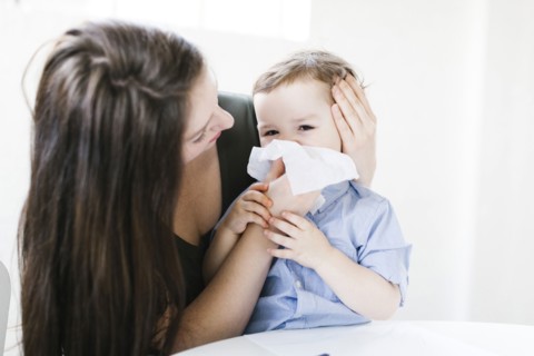 Young boy (4-5) blowing nose