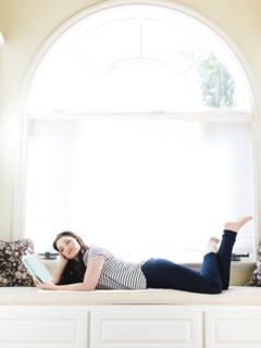 Woman lying on couch and reading book