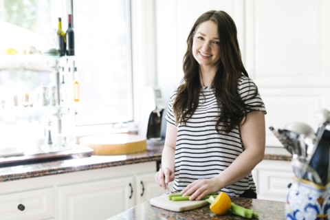 Woman cutting lemon and celery in kitchen
