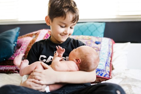 Young boy (6-7) holding brother (2-5 months)