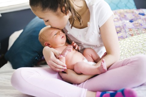 Girl (10-11) kissing brother with care (2-5 months)