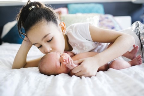 Girl (10-11) kissing brother with care (2-5 months)