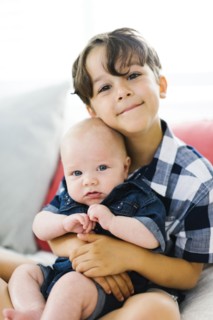 Young boy (6-7) holding brother (2-5 months)